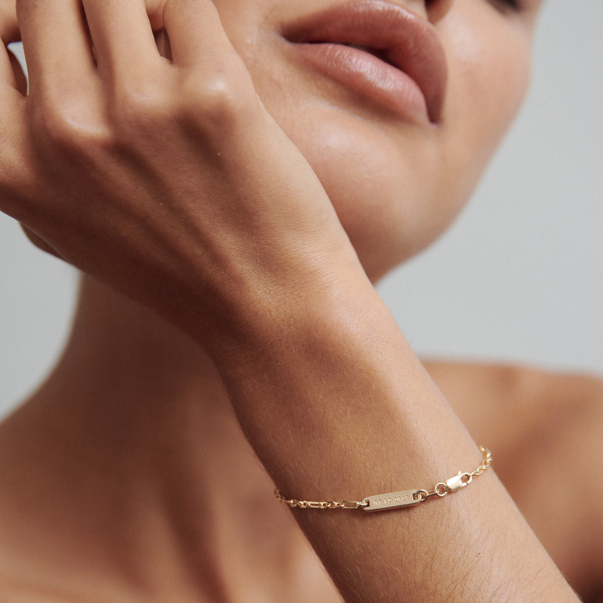 Elegant close-up of a woman's wrist showcasing a delicate gold chain bracelet with a small rectangular bar, highlighting minimalist luxury jewellery.