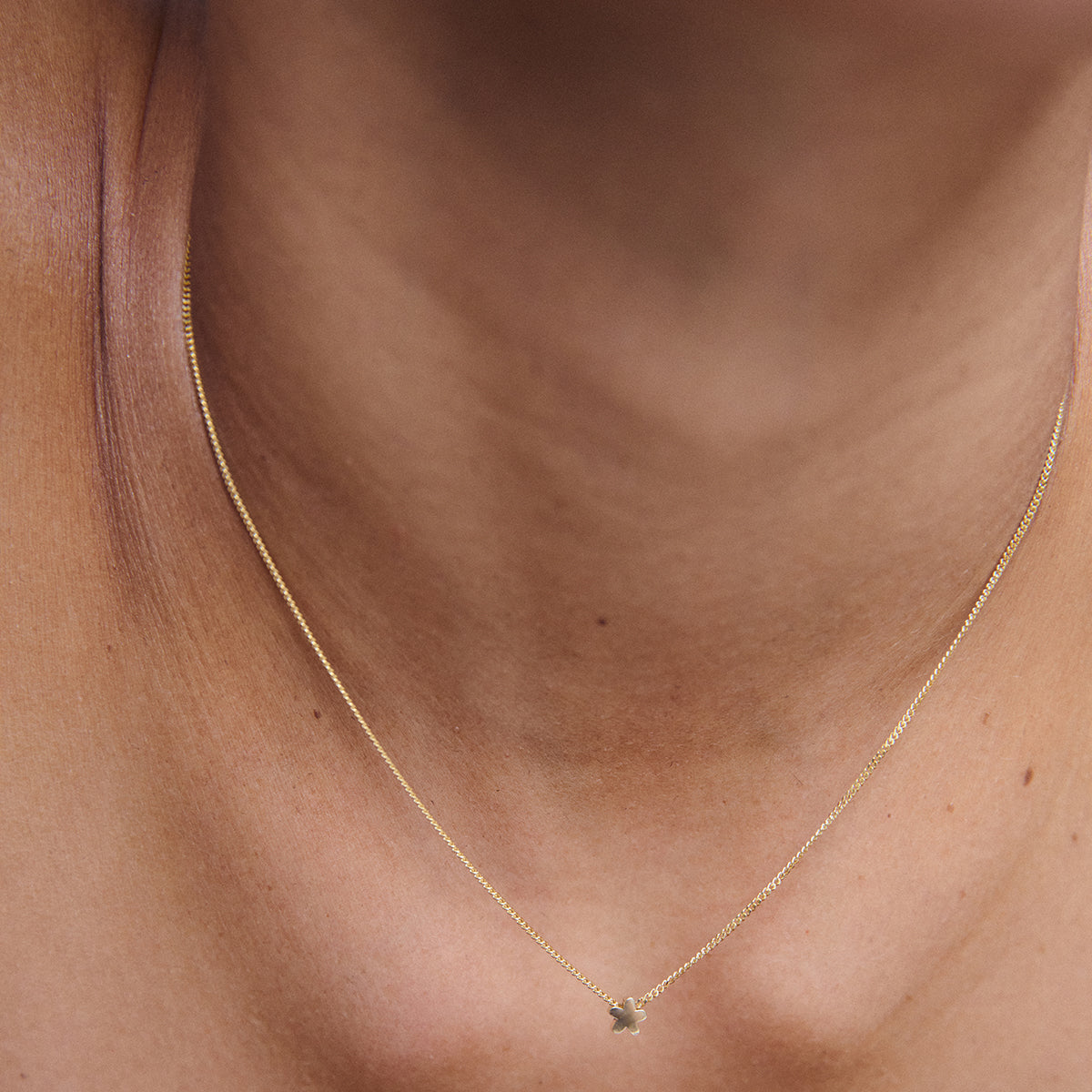 Elegant gold chain with a small pendant worn on a neck, showcasing minimalist luxury jewellery design.