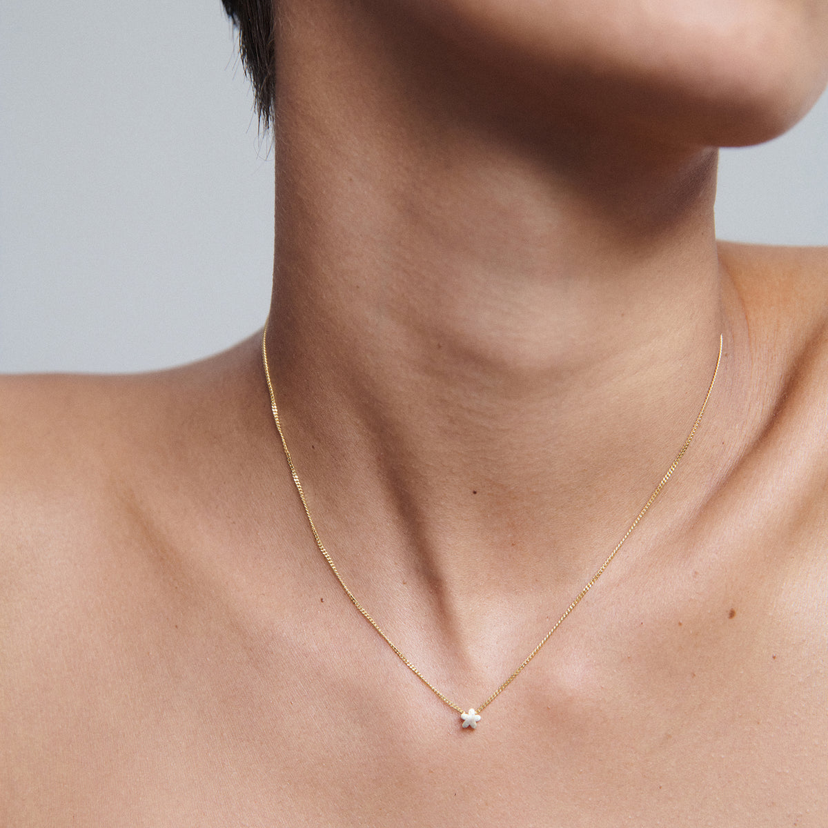 A delicate gold chain necklace with a small diamond pendant on a woman's neck, showcasing minimalist luxury jewellery.