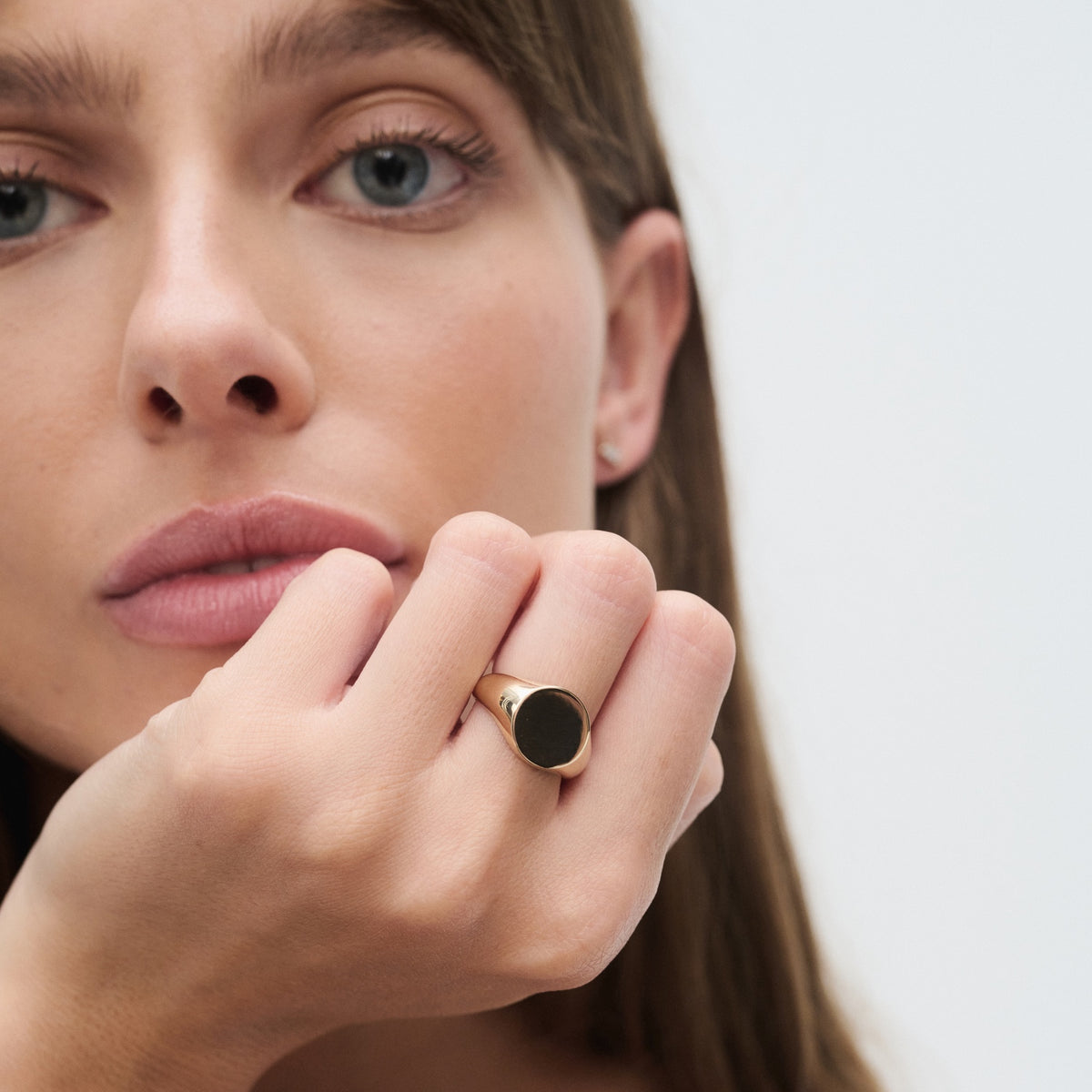 Woman with a gold ring featuring a large black stone on her finger, close-up portrait style. Luxurious jewellery focus.