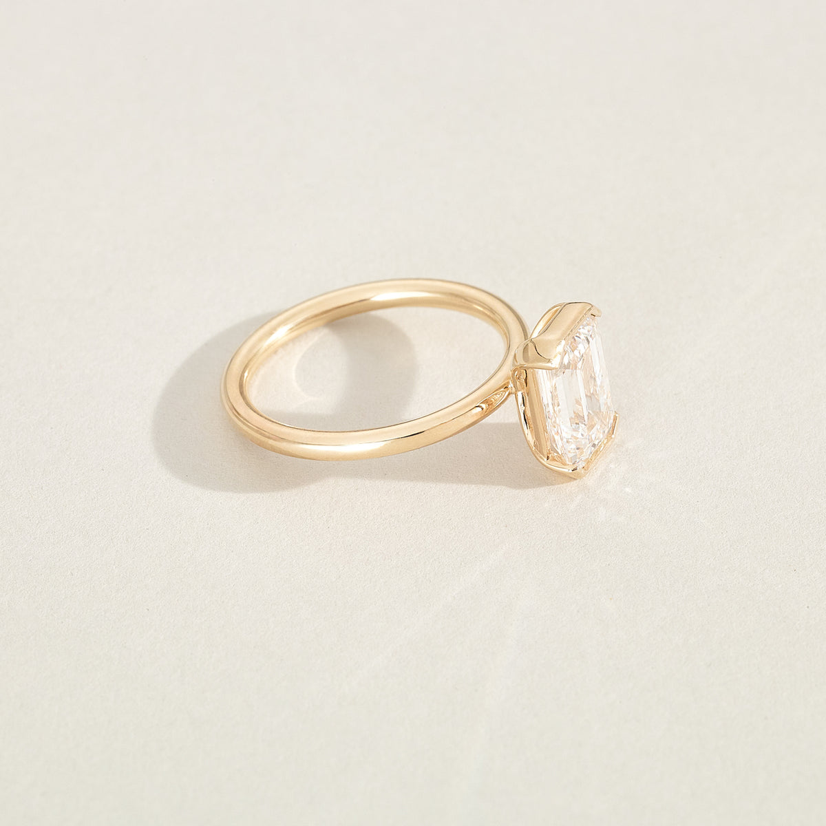 Gold ring with a diamond on a light beige background