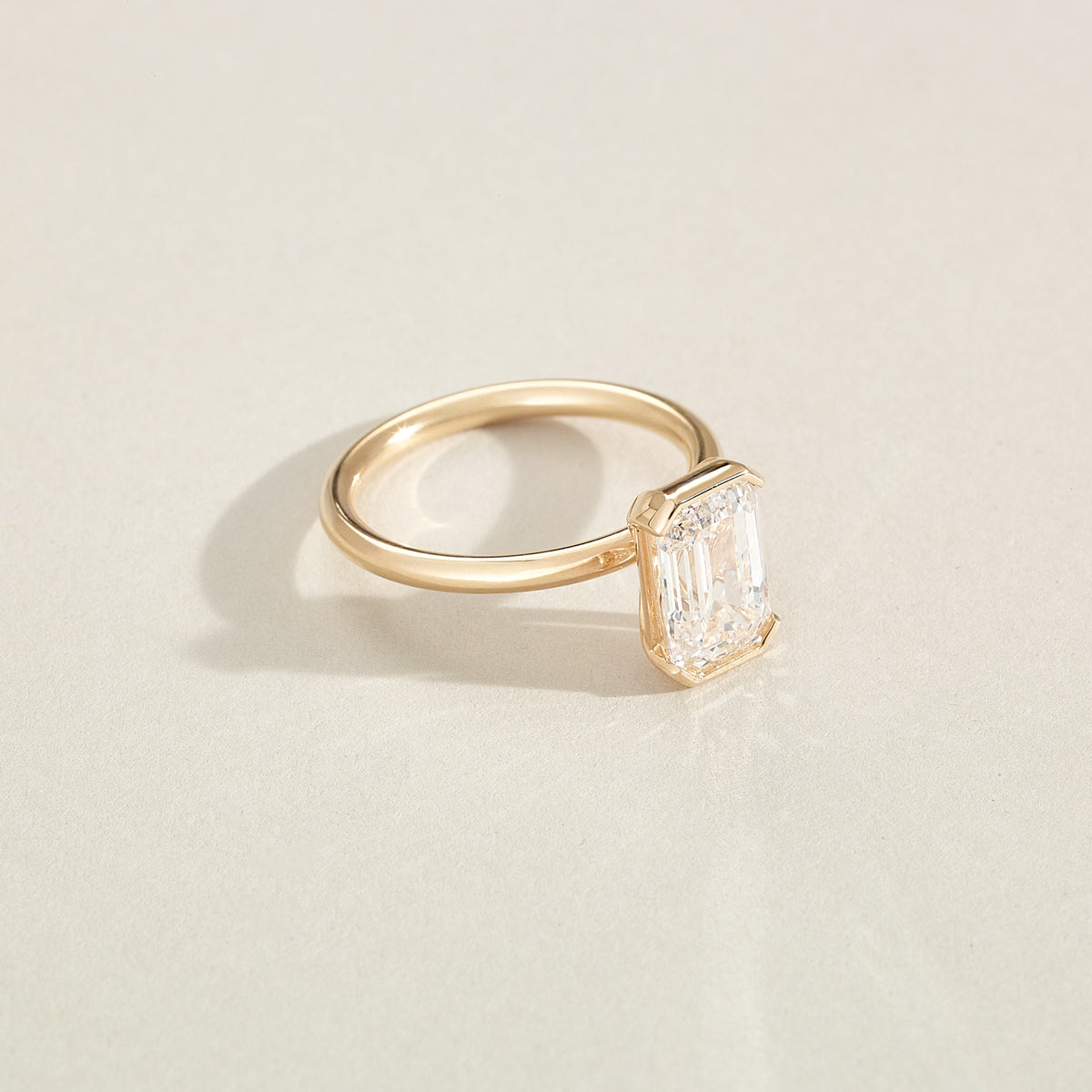 Gold ring with a diamond on a light beige background