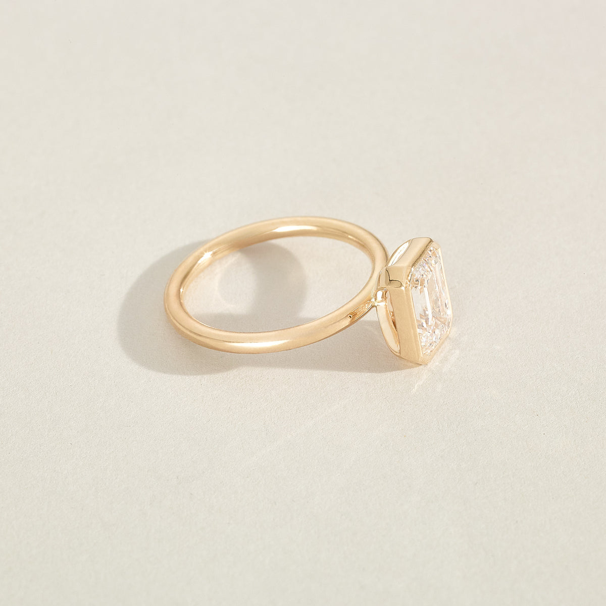 Gold ring with a diamond on a light beige background