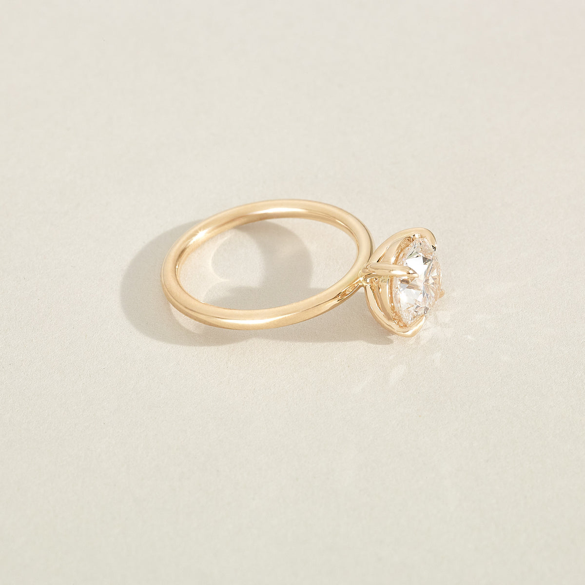 Gold ring with a diamond on a beige background
