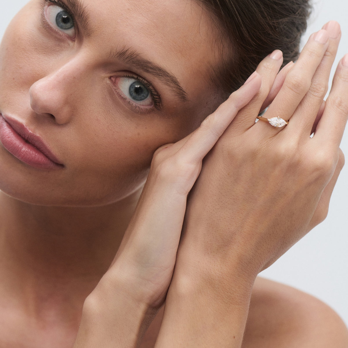 Woman showcasing an elegant diamond ring on her finger, hand near her face. Sophisticated and luxurious jewellery display.