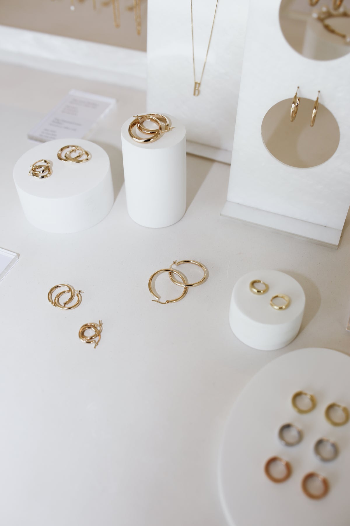 Assorted gold jewellery including rings, earrings, and necklaces displayed elegantly on white stands in a luxury showroom setting.