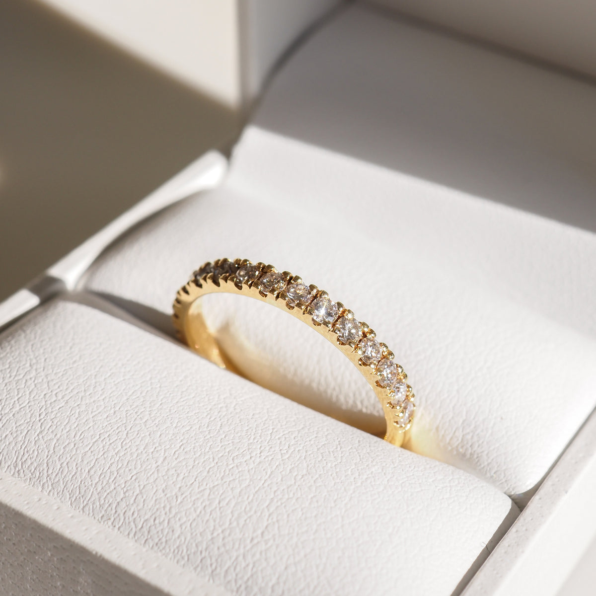 Gold round diamond wedding ring with bezel-set stones along a slim band