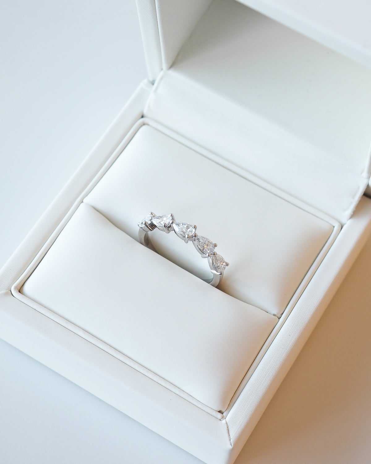 White gold diamond wedding ring with pear-shaped stones, side view in box