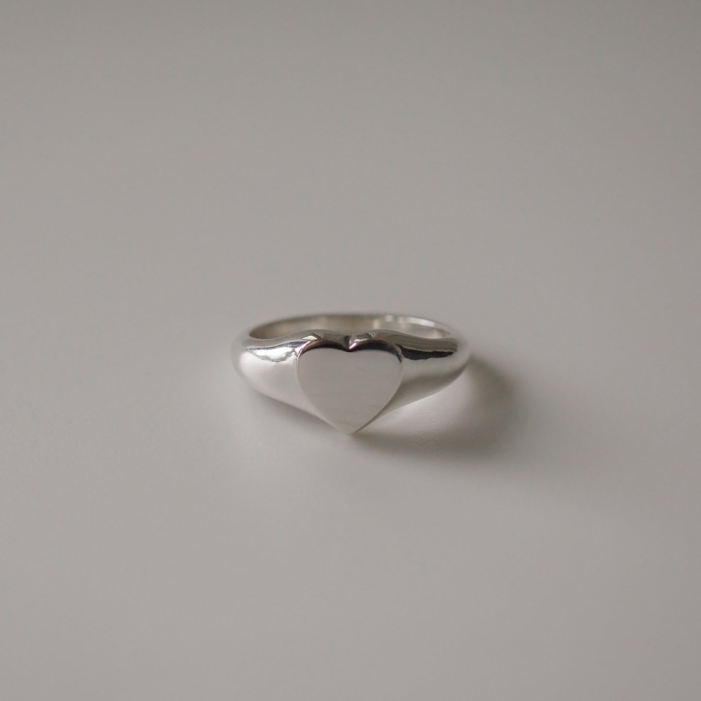 Elegant silver heart ring on a grey background, showcasing high-end luxury jewellery design. Perfect gift or statement piece.