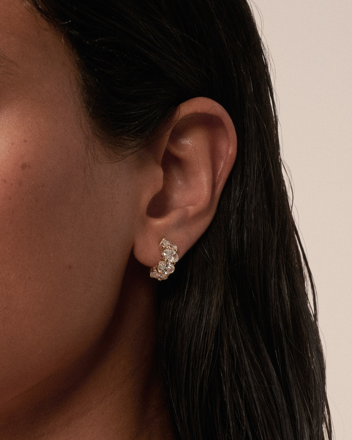 Oval lab-grown diamond hoop earrings in gold, close-up on ear