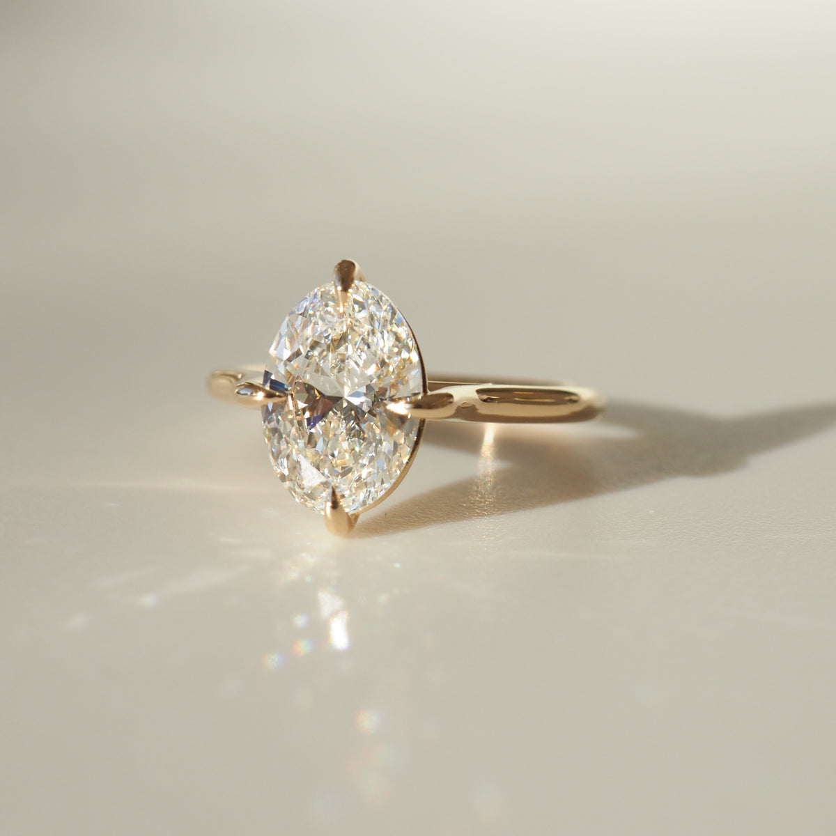 Gold ring with a marquise-cut diamond set in claw settings, reflecting soft light on a smooth surface. Luxury jewellery elegance.