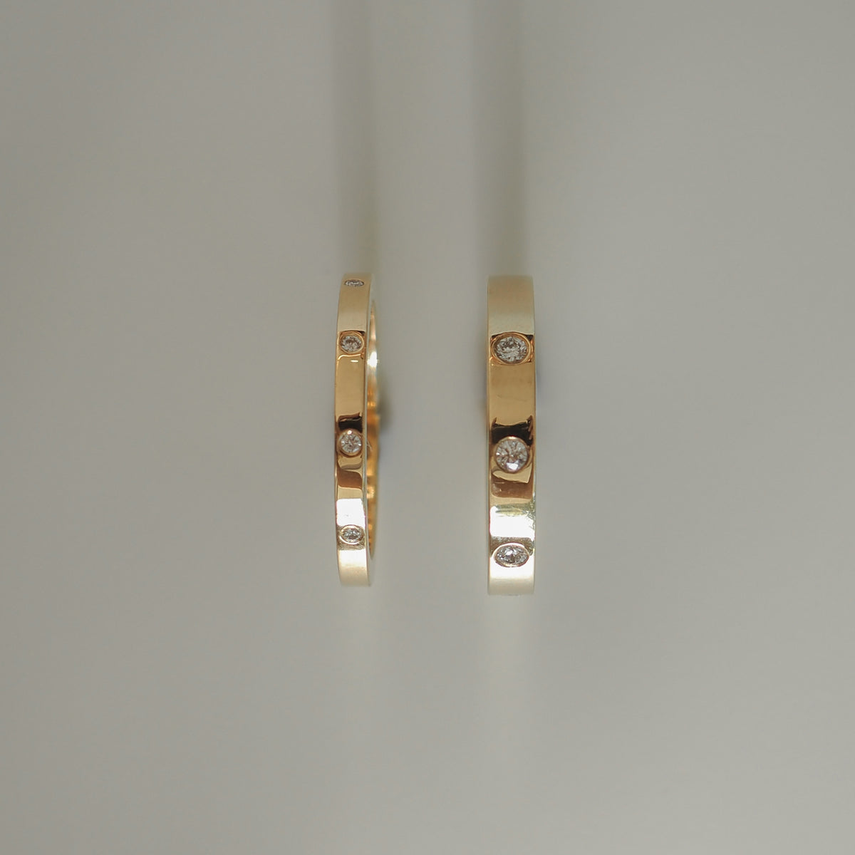Two gold rings with embedded round diamonds, showcasing luxury jewellery design on a light background.