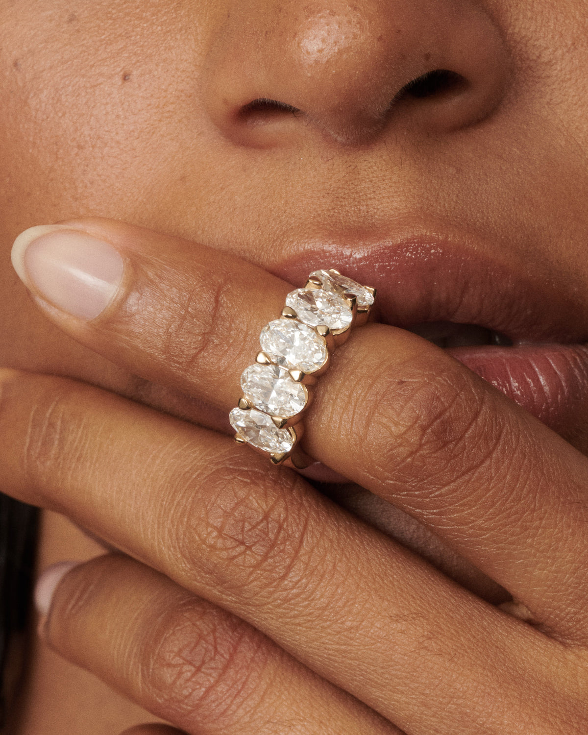 Oval diamond ring with five bezel-set stones on a slim band