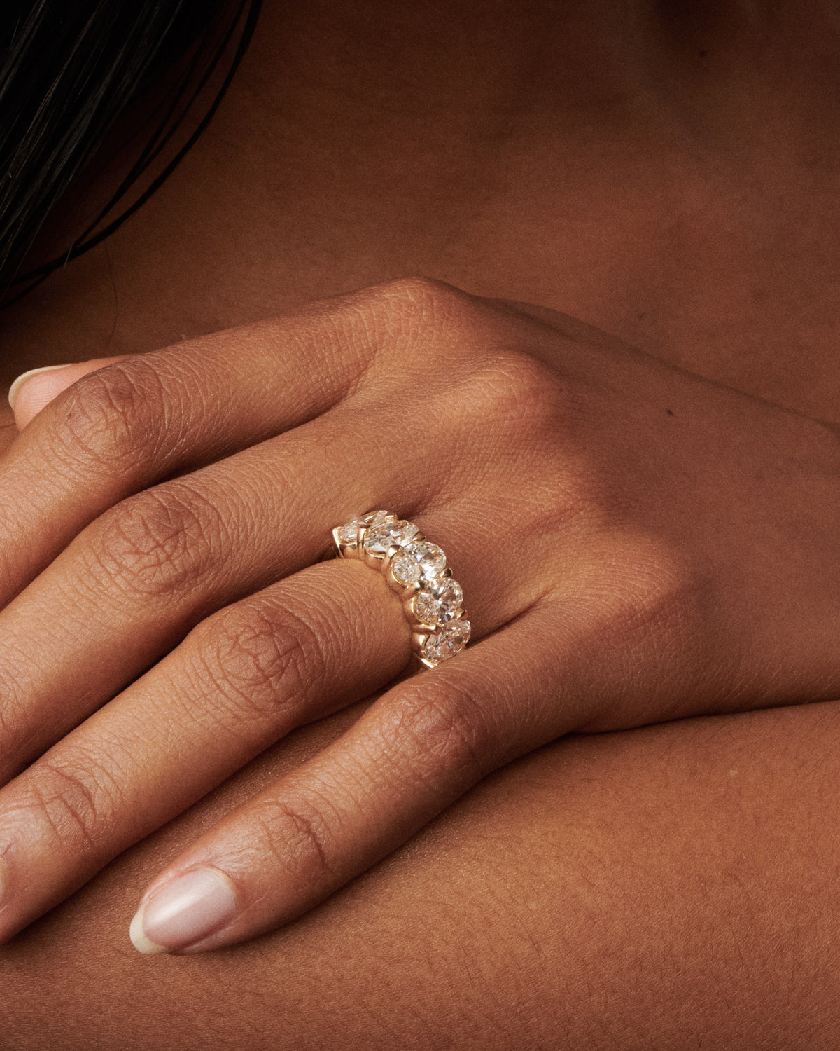 Oval diamond ring with five stones on a slim band, worn on finger