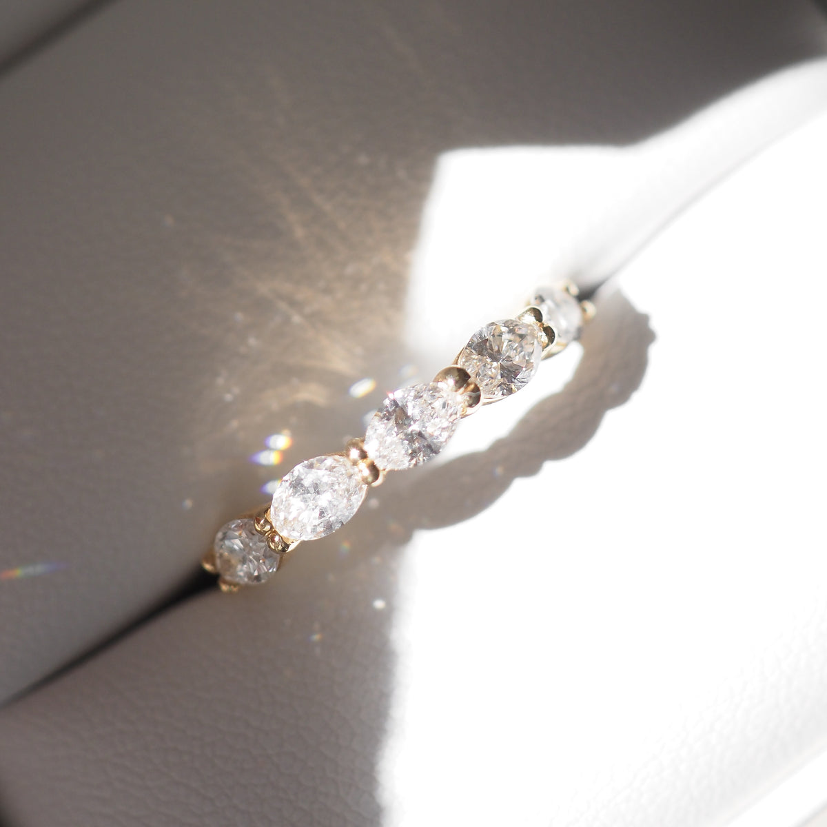 Gold ring with five sparkling diamonds in a white jewellery box, showcasing luxury and elegance in fine jewellery design.