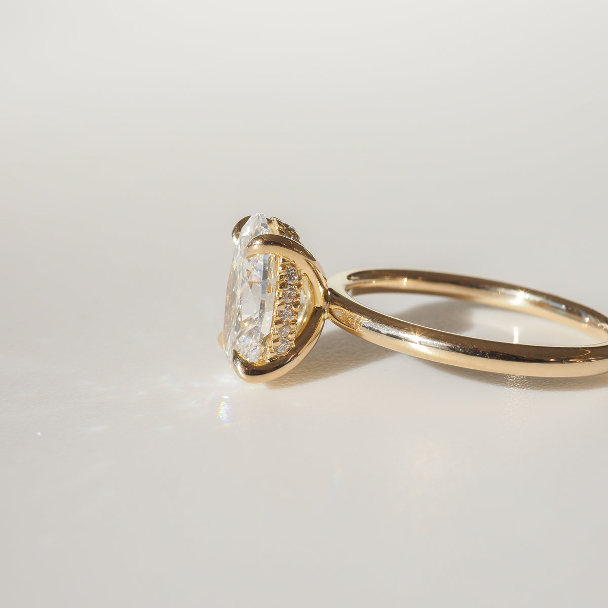 Gold ring featuring an oval-cut diamond in a raised setting, displayed against a neutral background, showcasing luxury jewellery craftsmanship.