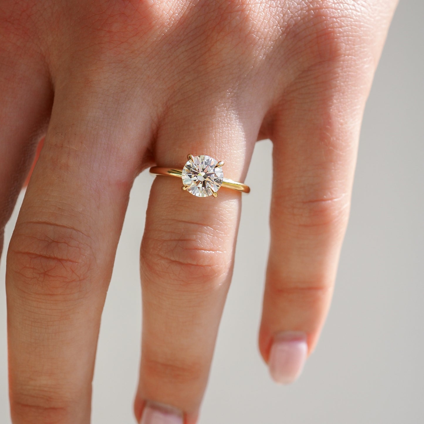 Elegant hand wearing a gold ring with a large round diamond, showcasing luxury jewellery.