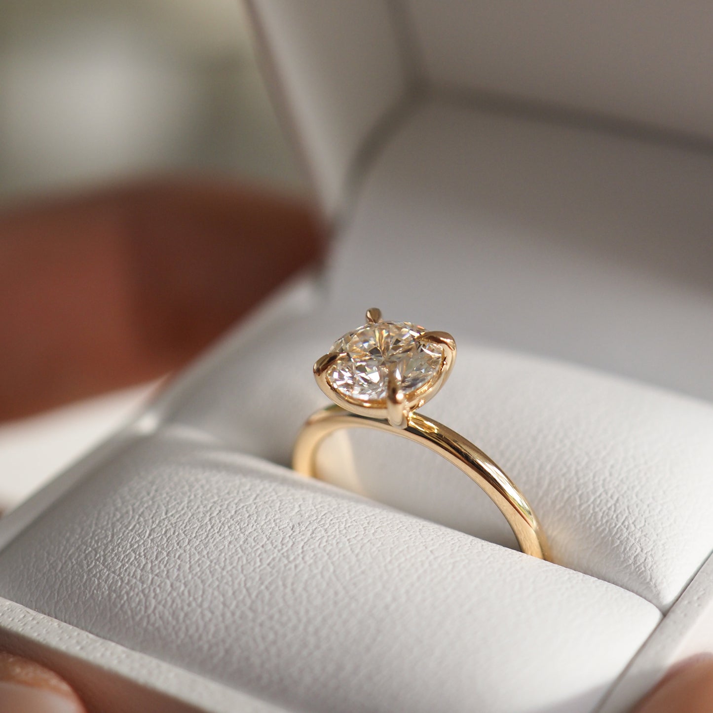 Engagement ring with a large, sparkling diamond set in a gold band, presented in an open jewellery box.