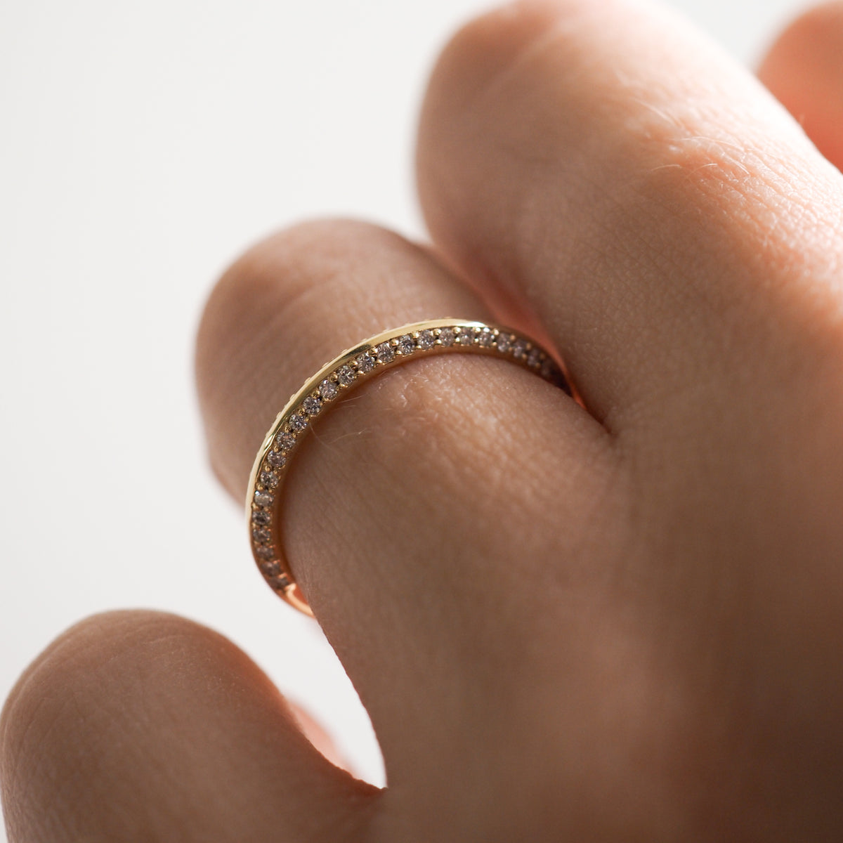 Close-up of a hand wearing a gold band encrusted with small diamonds, capturing the luxury and elegance of fine jewellery.