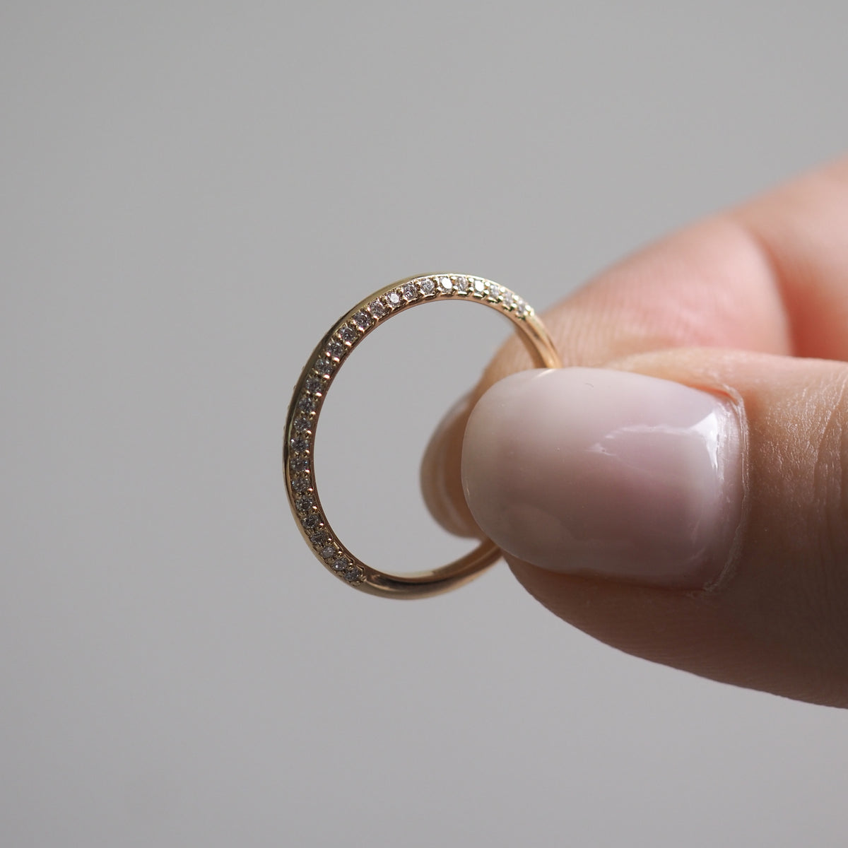 Hand holding an elegant gold ring with small diamonds, showcasing luxury jewellery craftsmanship. Perfect for high-end jewellery enthusiasts.