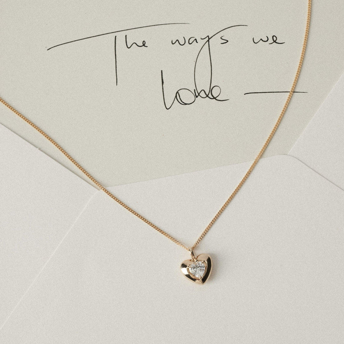 White and cream envelope with yellow gold heart pendant diamond necklace draped