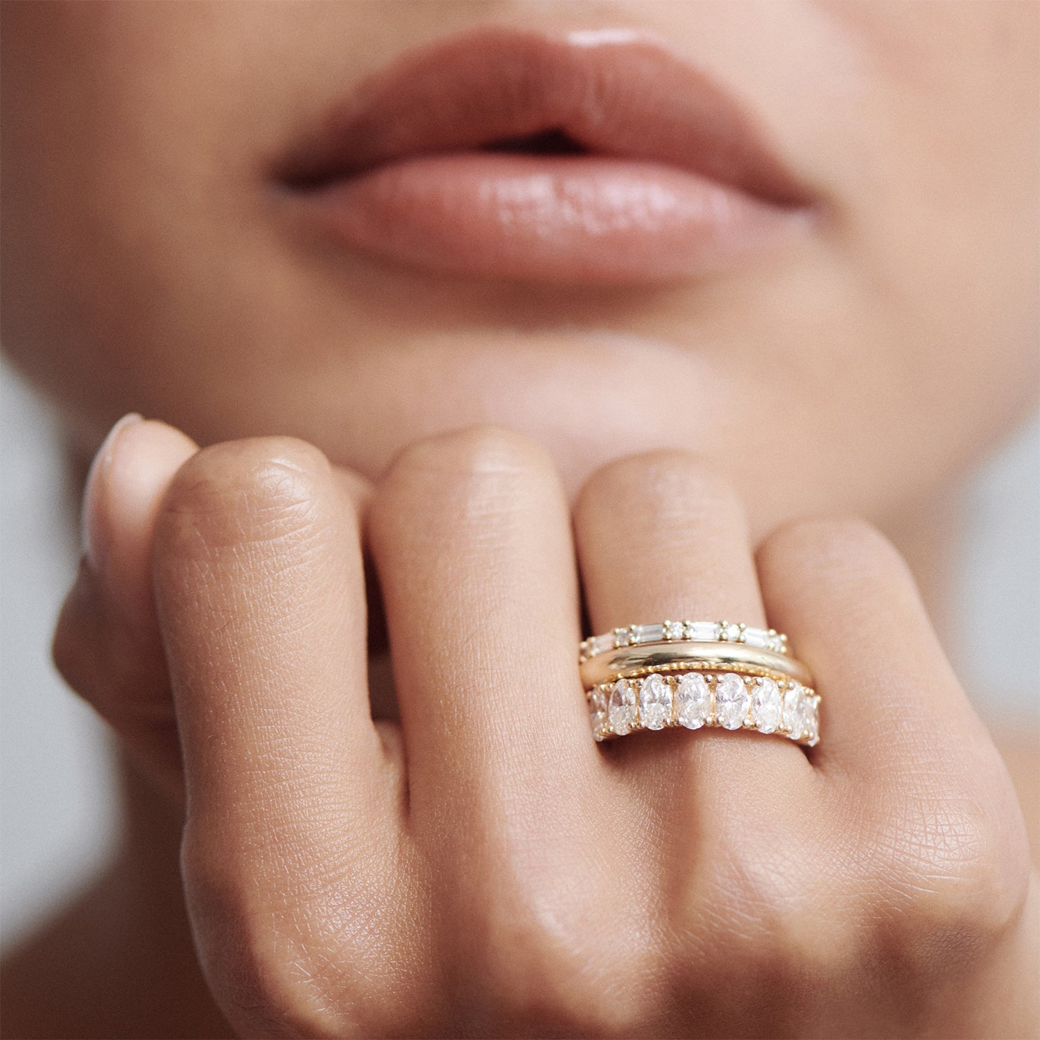 Close-up of a woman's hand adorned with elegant gold and diamond rings against her lips, showcasing luxury jewellery craftsmanship.