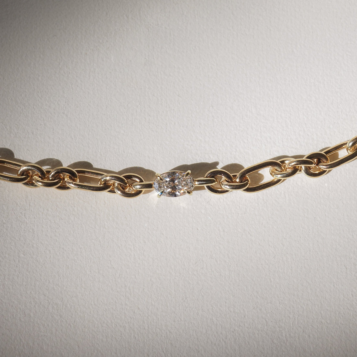 Gold chain necklace featuring an elegant oval diamond centerpiece, set against a light background, showcasing luxury jewellery design.