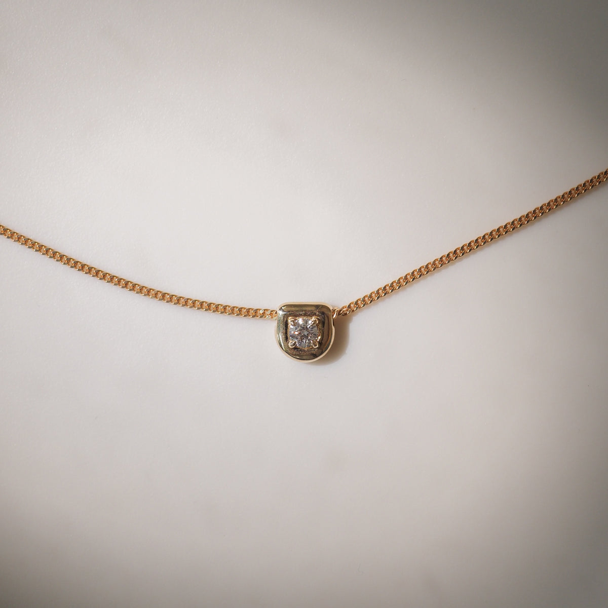 Gold chain necklace with a square diamond pendant set in gold, minimalist luxury jewellery design.