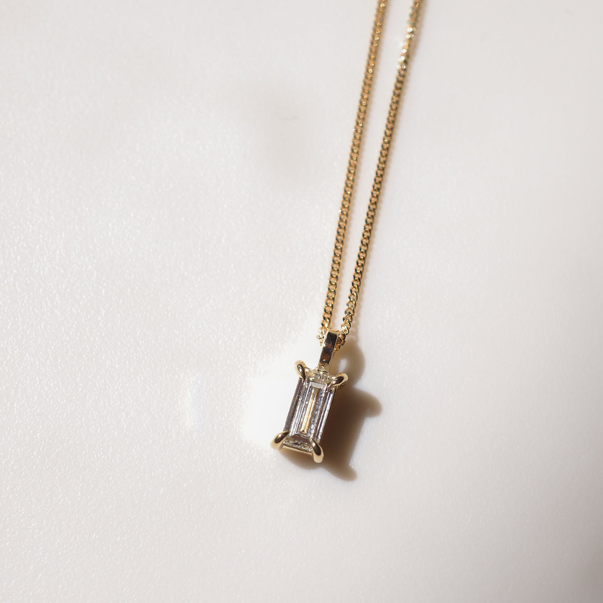 Gold chain necklace featuring a radiant, rectangular gemstone pendant. Subtle elegance in high-end jewellery design.