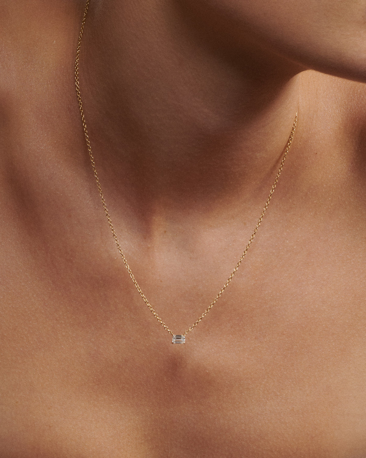 Gold necklace with a small pendant on a person's neck