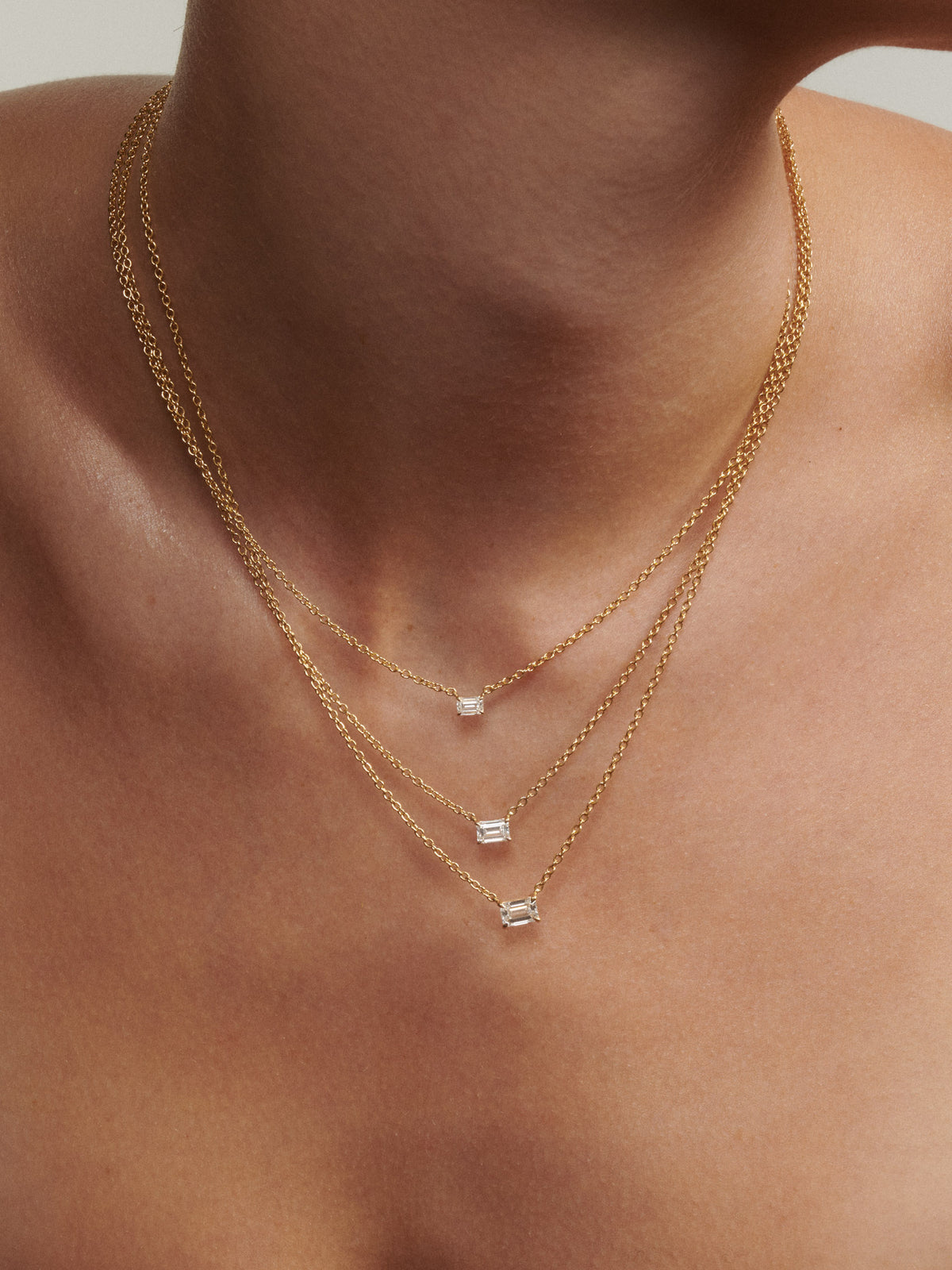 Gold necklaces with gemstones on a person's neck [text overlay: 0.25ct, 0.5ct, 0.75ct (top to bottom)]