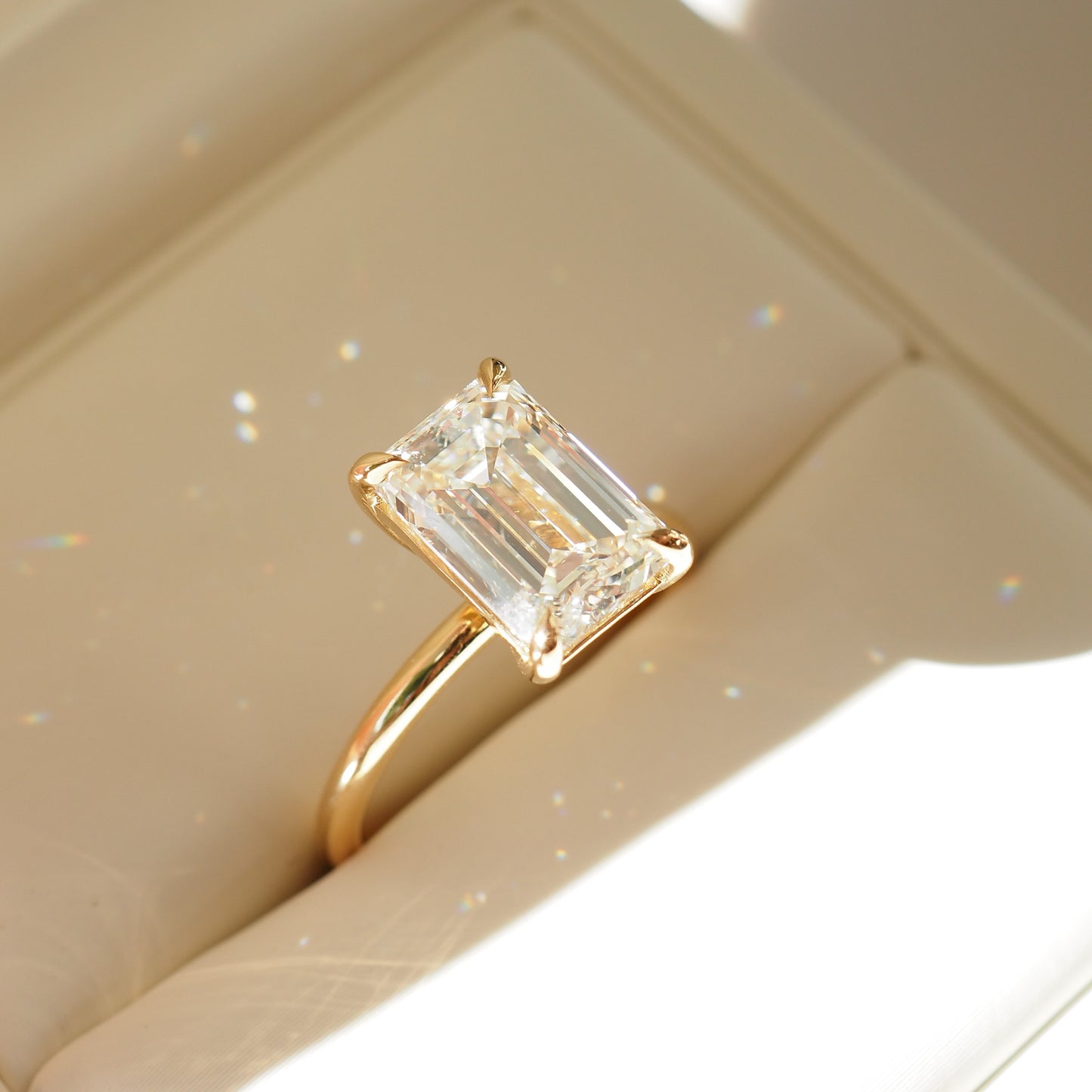 Emerald cut diamond ring with a gold band in a cream box. Luxurious, elegant jewellery design.