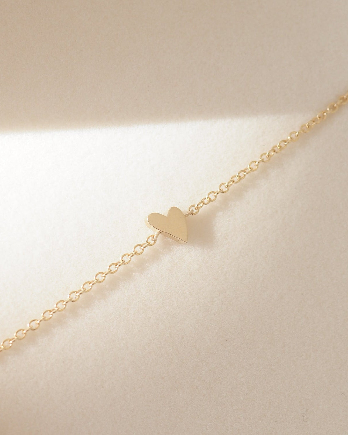 Gold heart-shaped bracelet on a beige background