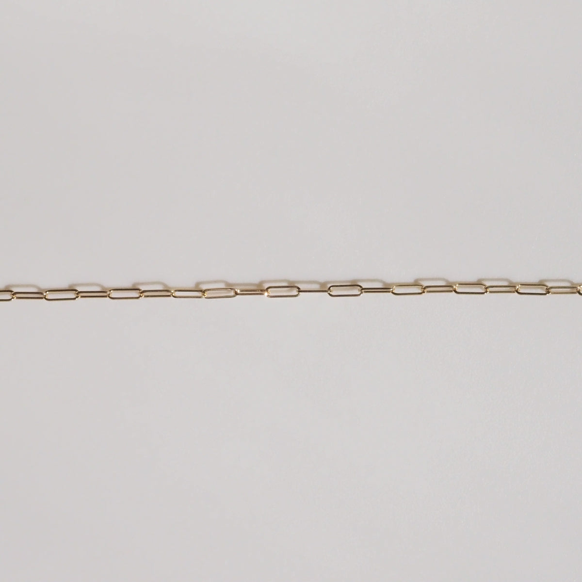 Delicate gold chain necklace displayed on a light background, featuring evenly spaced, rectangular links. Perfect for luxury jewellery enthusiasts.