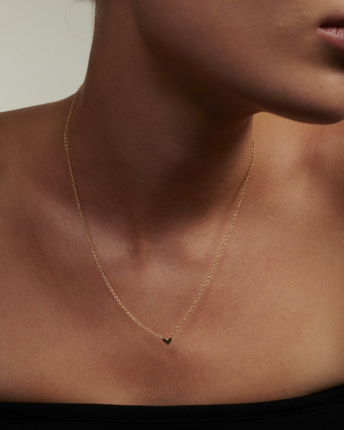 Fine gold necklace with small hand-drawn heart charm fixed at center.