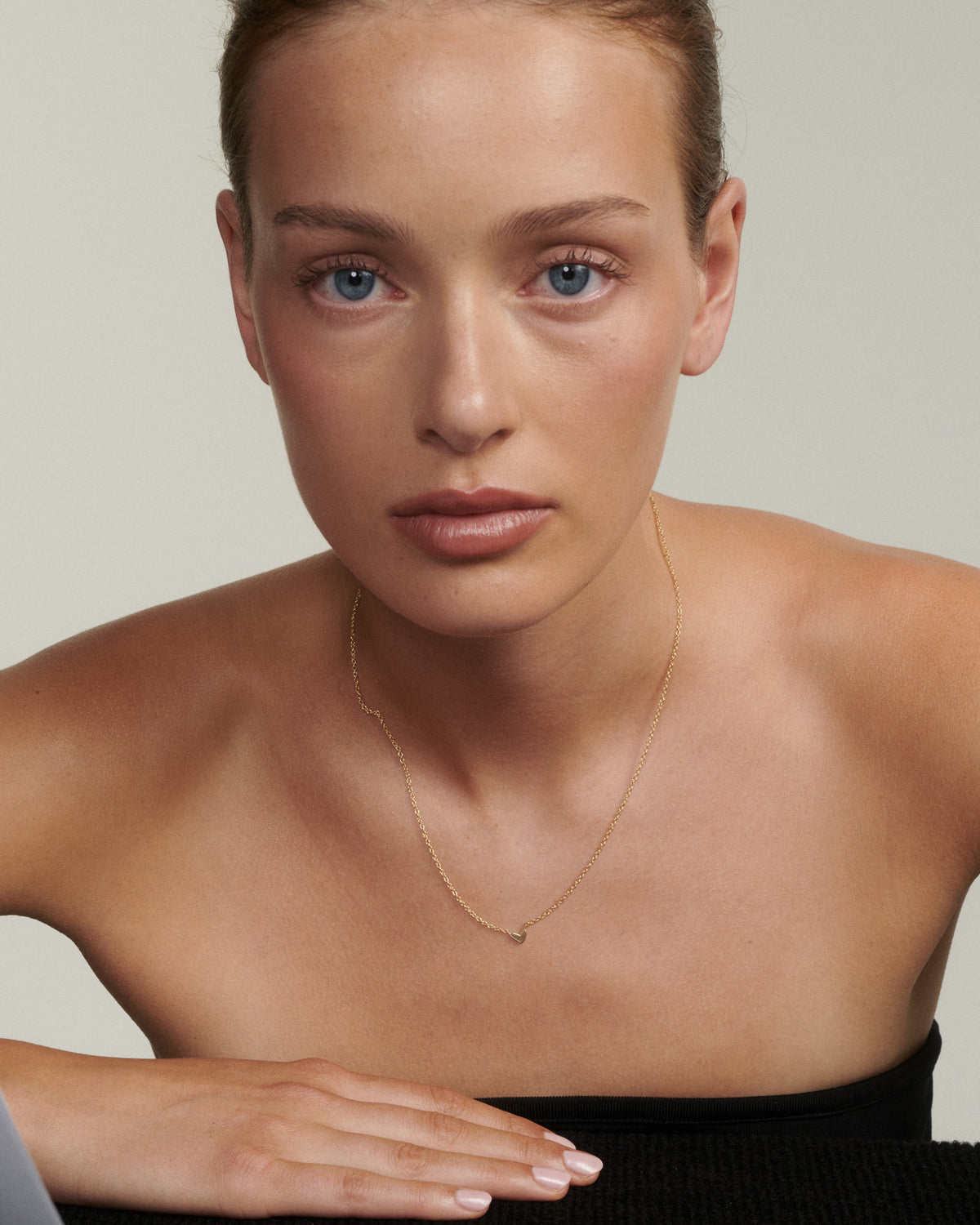 Gold fixed charm necklace with a small hand-drawn heart pendant at neckline.