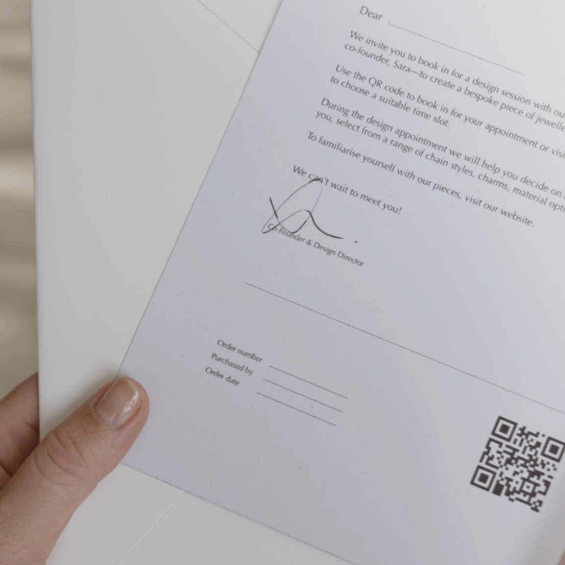 Invitation to jewellery design session with QR code, signature, and handwritten order form held in hand. High-end bespoke jewellery experience.