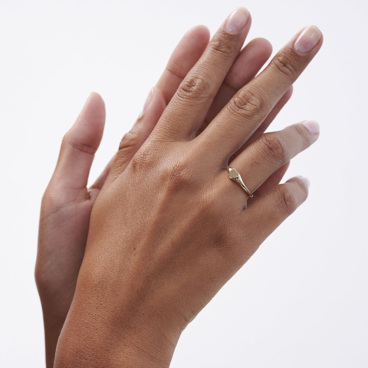 Close-up of a hand wearing a minimalist gold geometric ring. The ring is positioned on the index finger against a plain white background.