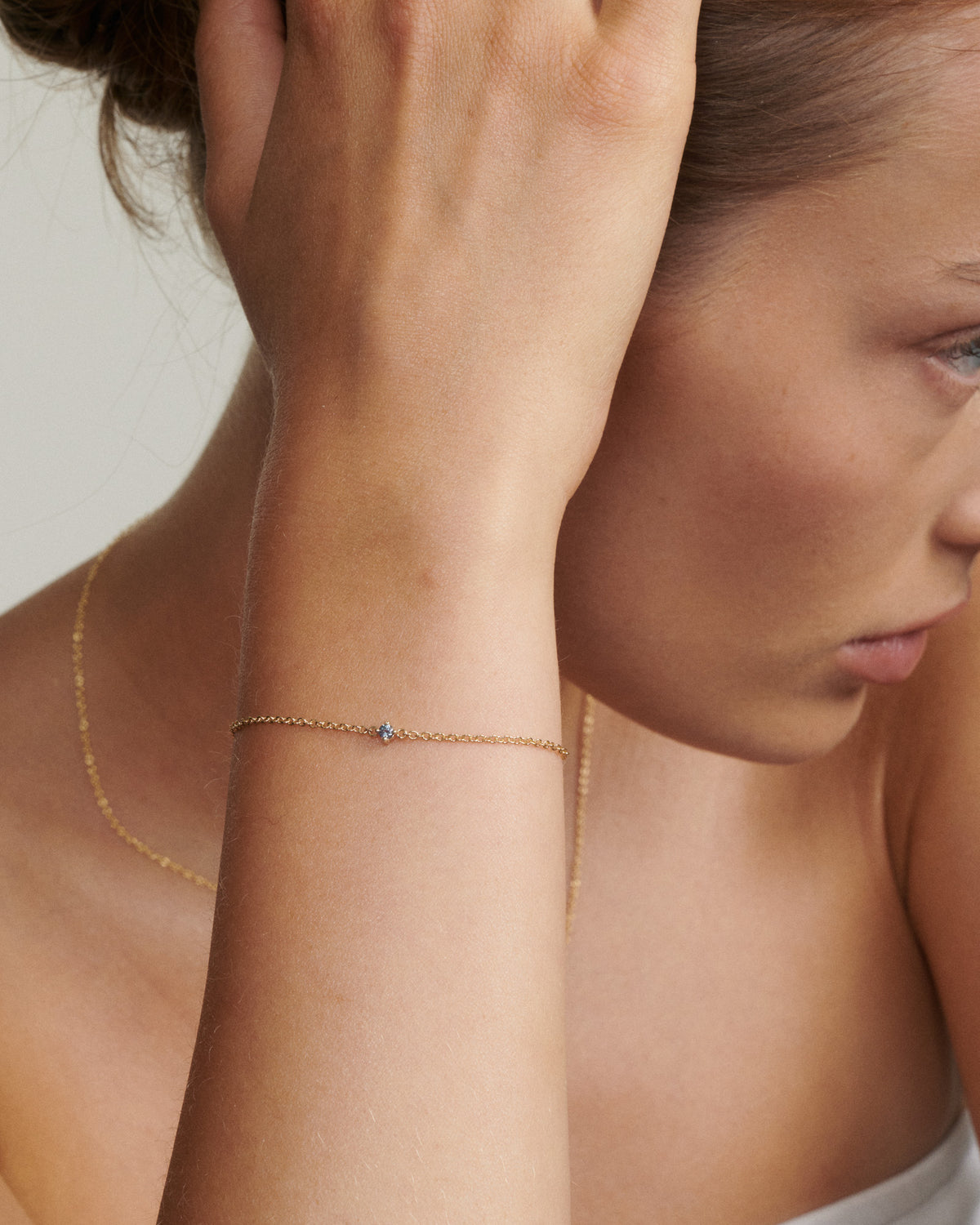 Close-up of a woman wearing a delicate gold necklace with a small pendant.