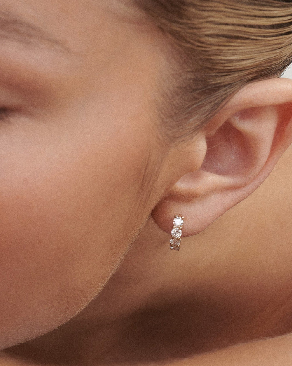 Close-up of a woman wearing a diamond earring.