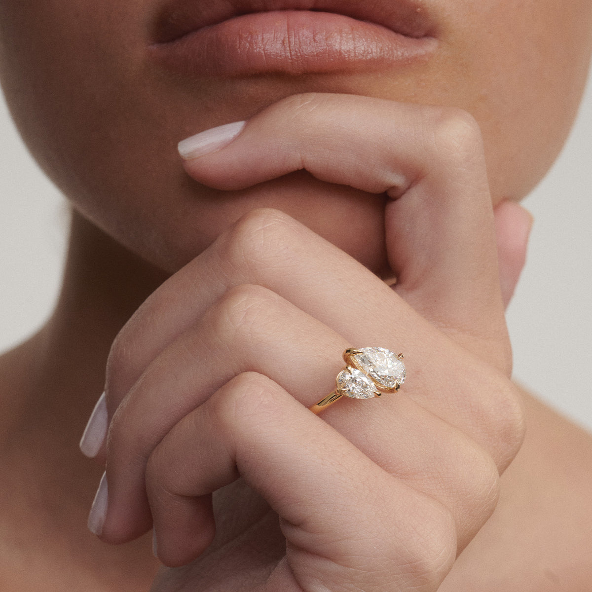 Yellow gold pear-cut diamond engagement ring worn on hand