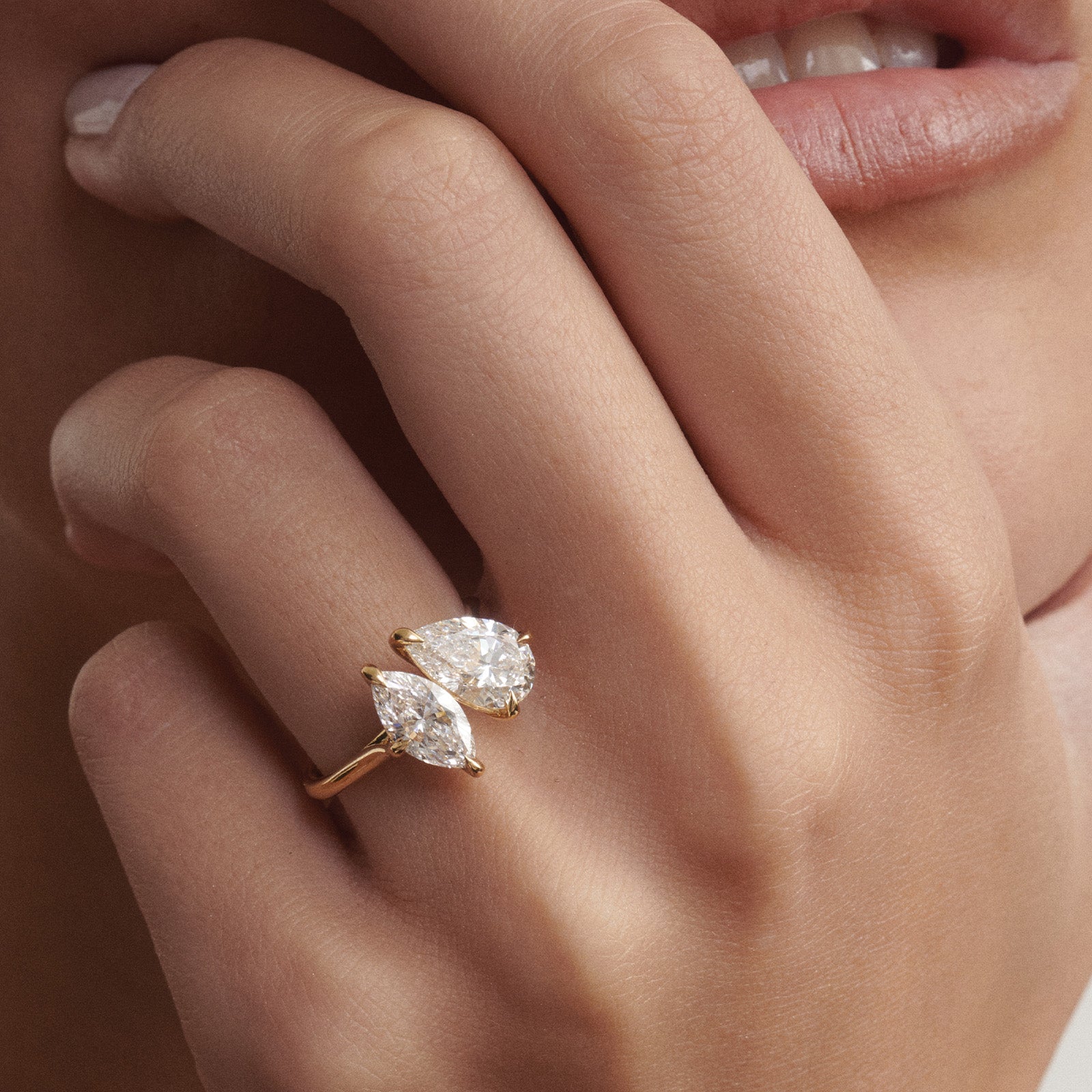 Close-up of a hand wearing a Toi Et Moi gold ring with two diamonds.