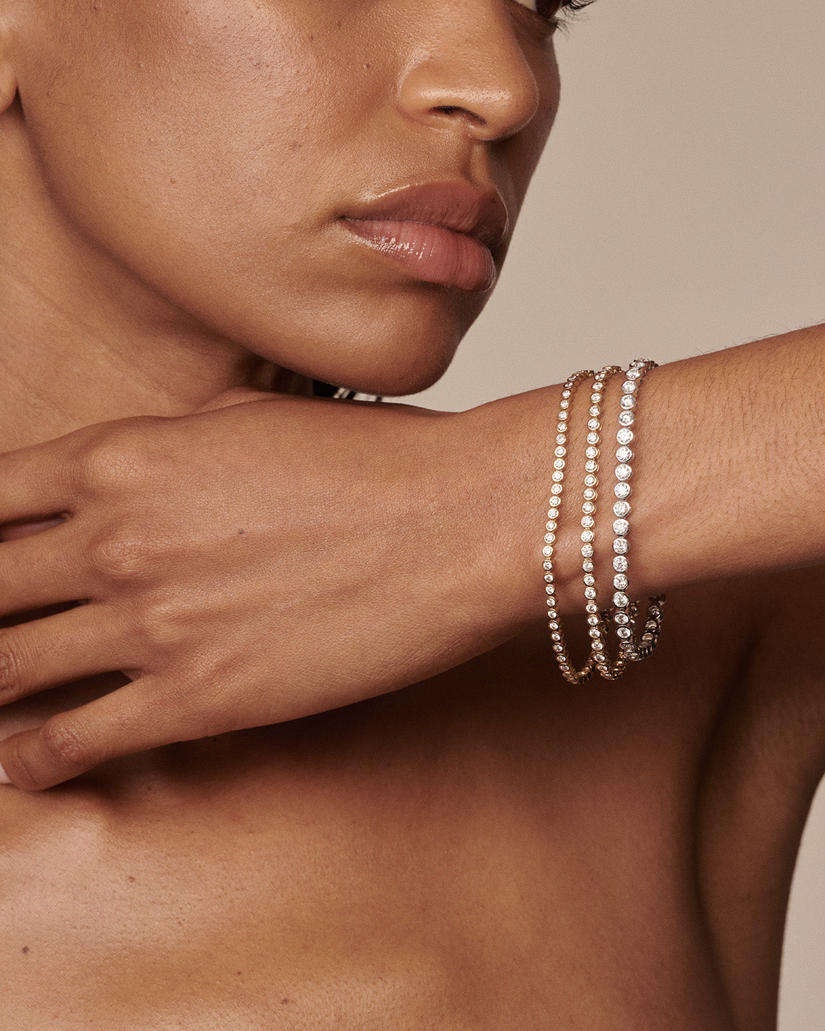 A close-up of a model's wrist wearing three delicate beaded bracelets in white, champagne, and gold tones, set against a warm beige background.
[text overlay: 2ct, 3ct & 5ct (left to right)]