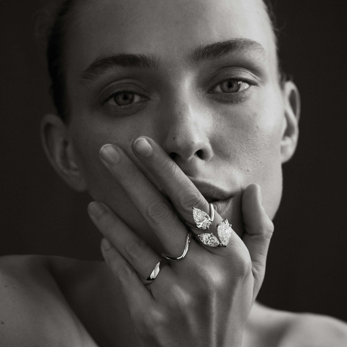 Black and white portrait of a person wearing diamond jewelry with a dark background