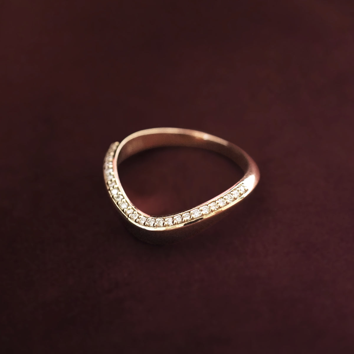 Gold ring with small diamonds on a dark brown background