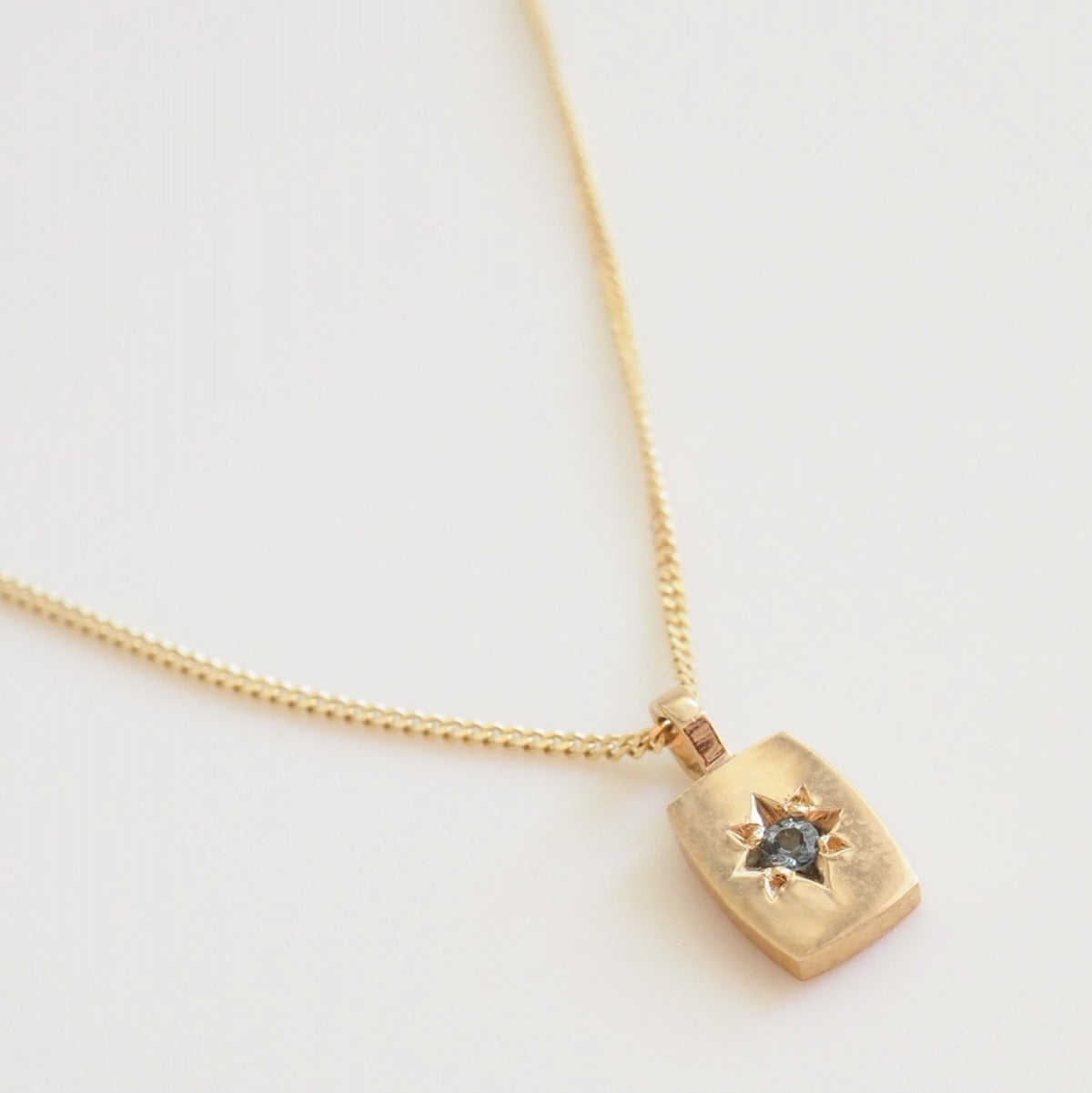 Gold necklace with a pendant on a light gray background