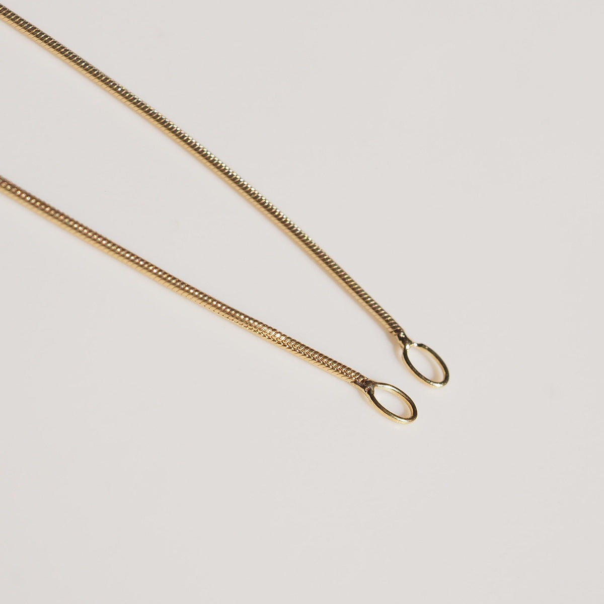 a flat lay of our Snake Chain Drops styled on a cream background