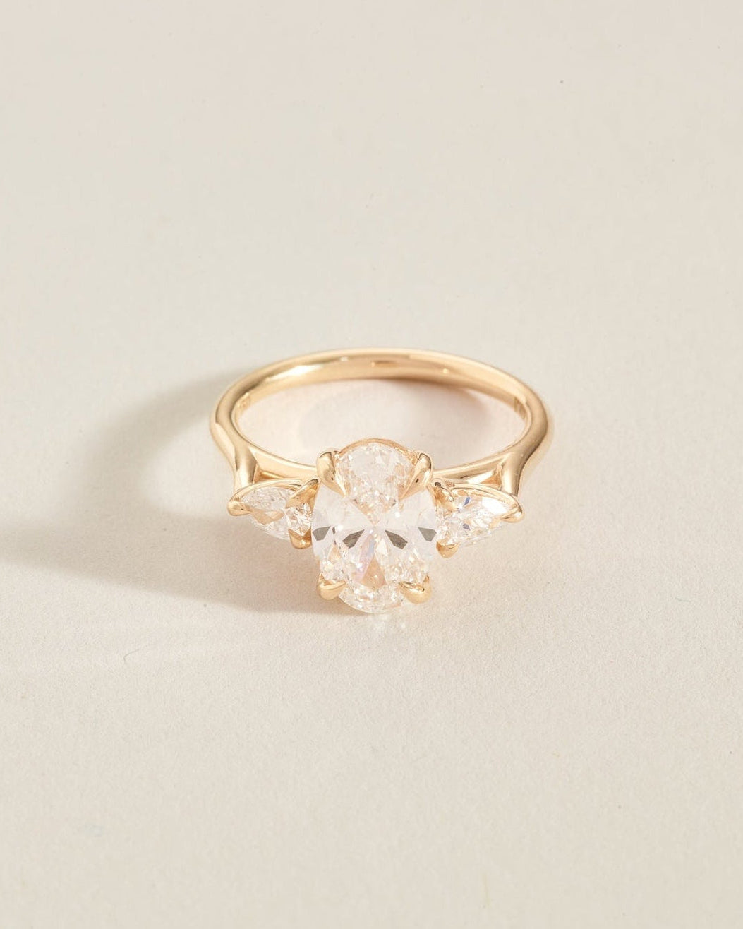 Gold ring with clear gemstones on a light beige background