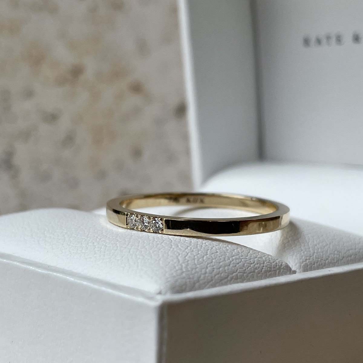 Elegant gold band with small diamonds, displayed on a cushioned box. Perfect for luxury jewellery lovers.