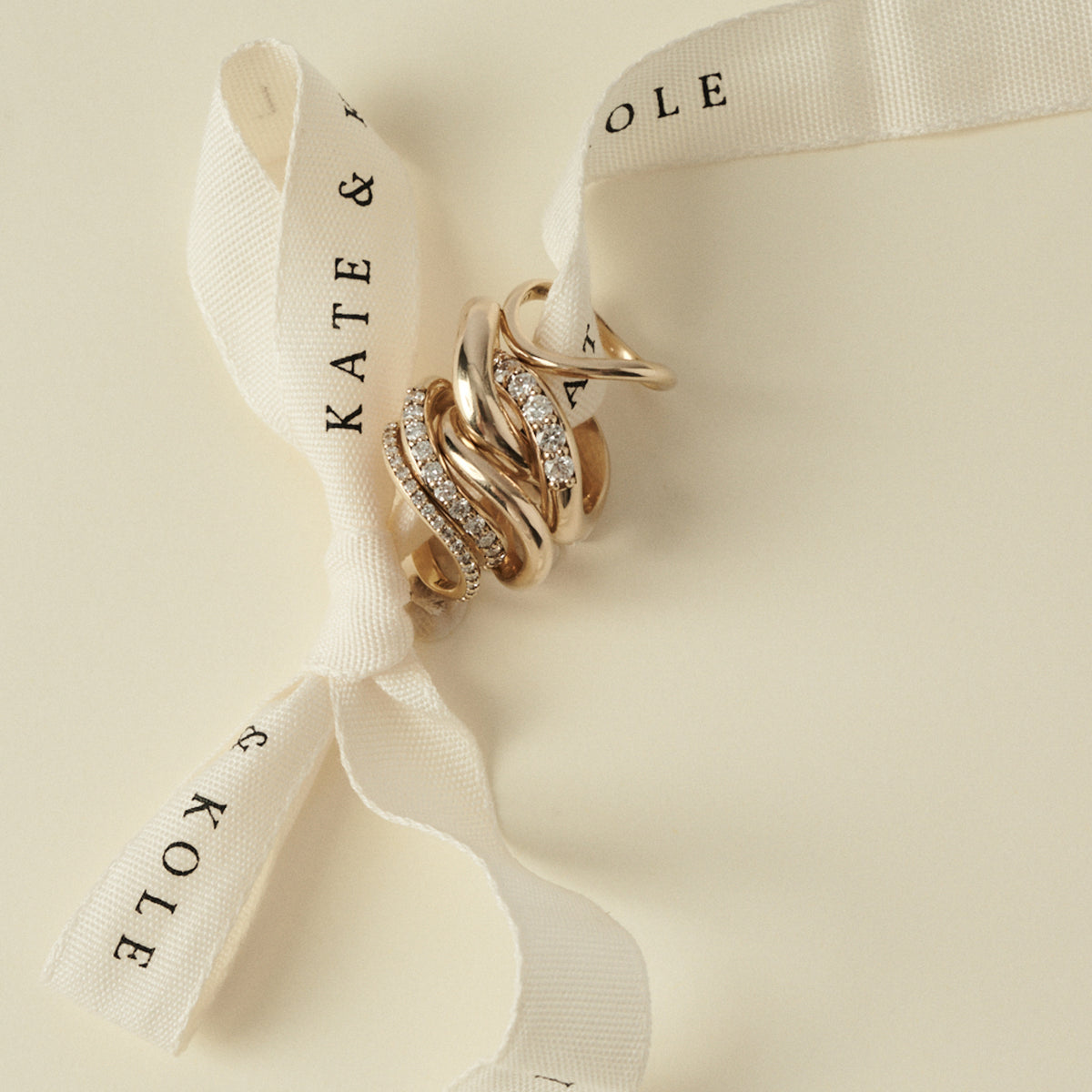 Gold rings on a ribbon with 'KATE & KOLE' branding